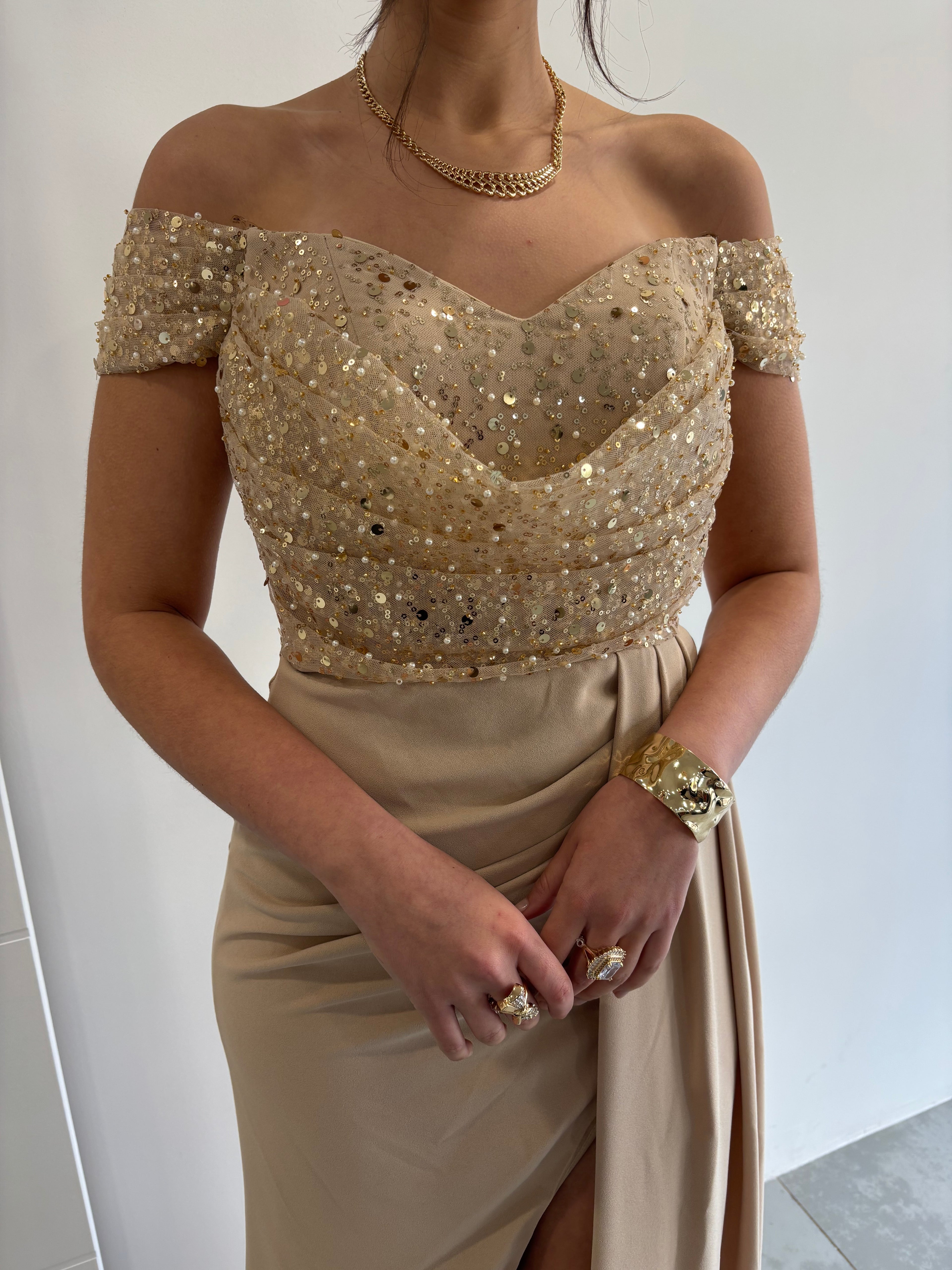 Robe de soirée beige et dorée bustier pailleté avec col bateau, fente sur le côté et détails en tissu plissé