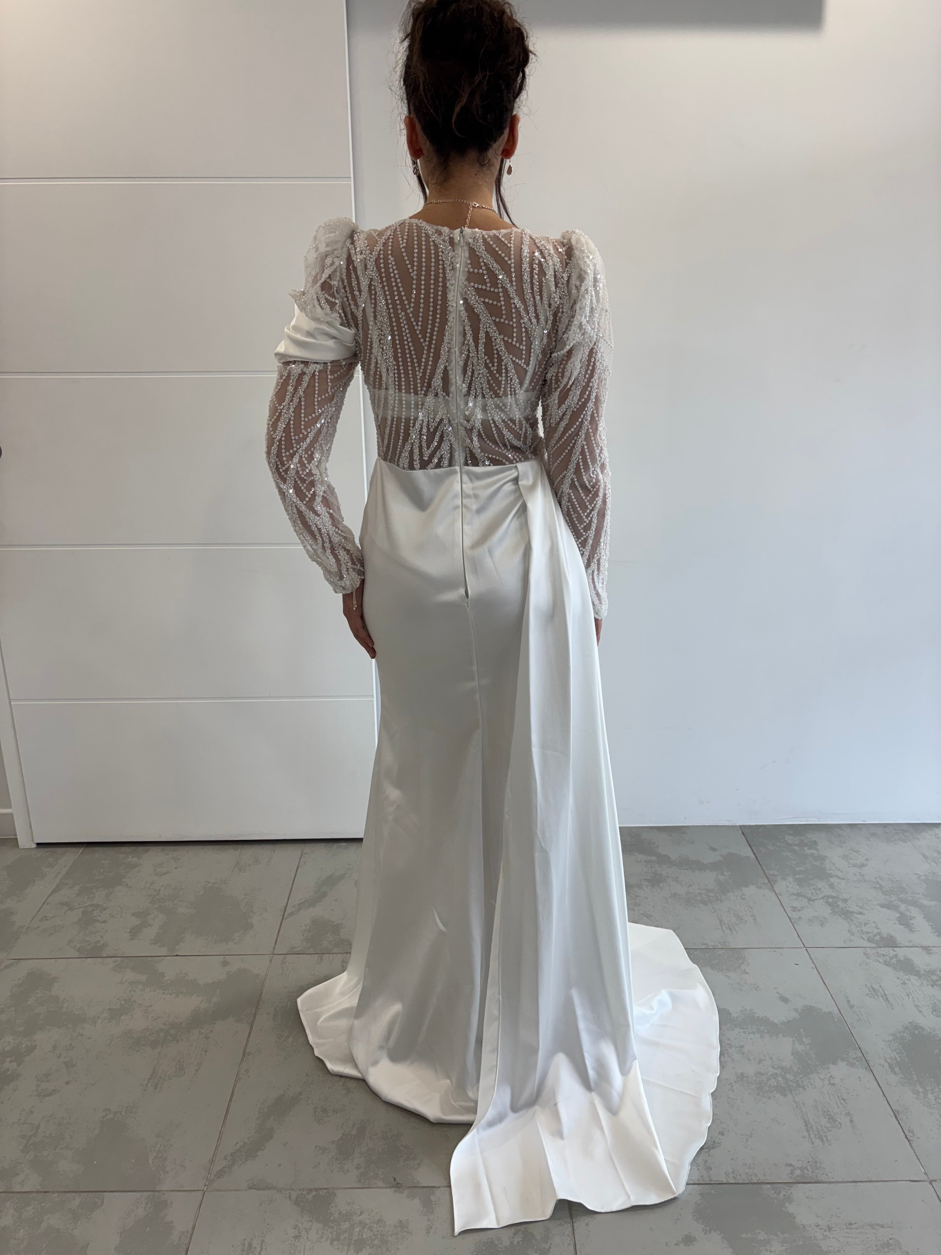 Robe de mariée blanche élégante à manches longues transparentes perlées avec fente sur le côté et traîne vue de dos 