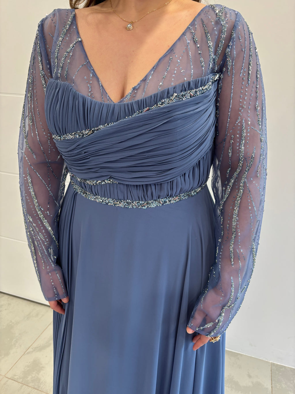 Robe de soirée bleue à coupe évasée, buste plissé orné de paillettes, col en V et manches longues transparentes pailletées - vue de près 
