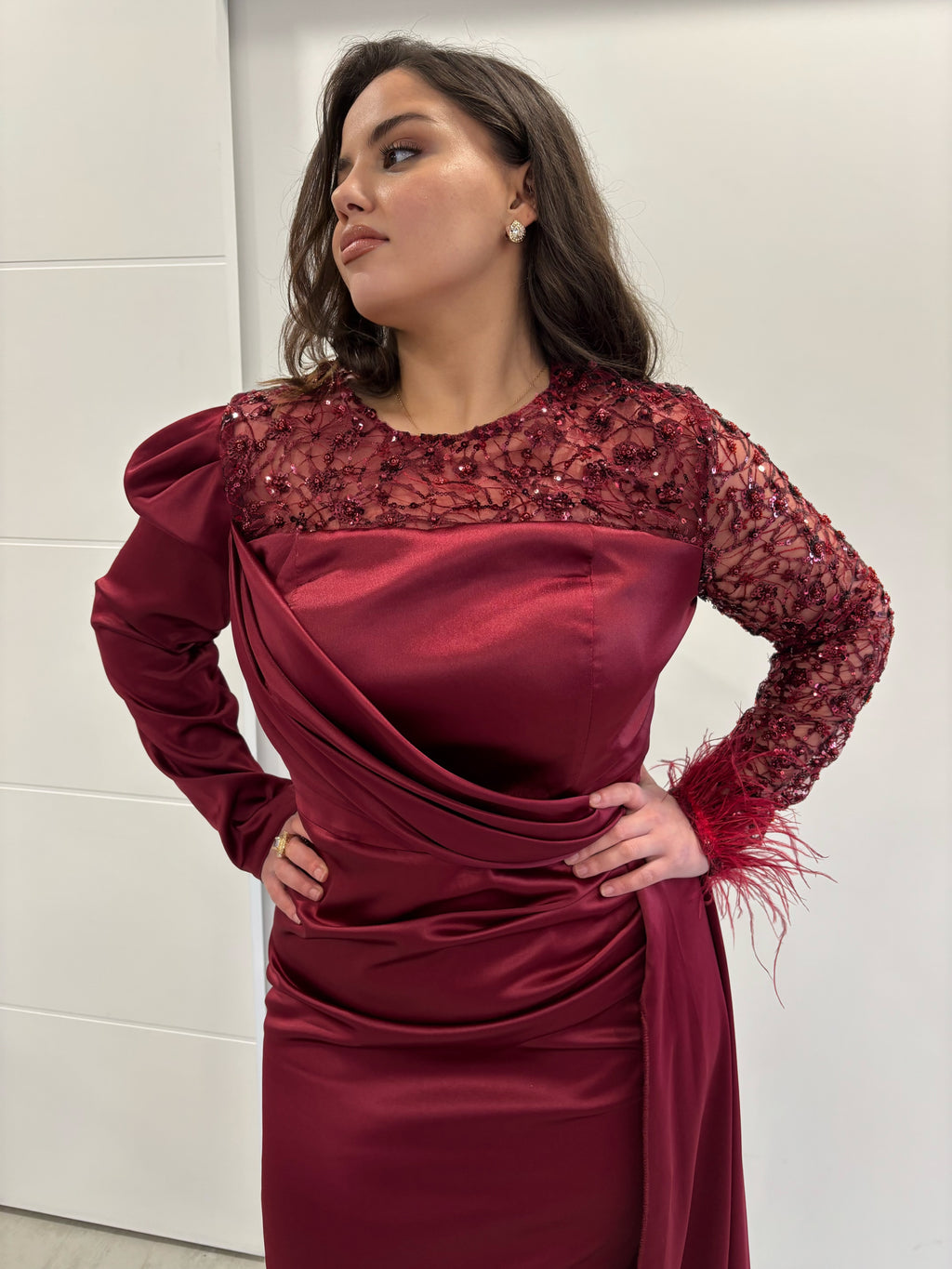 Robe de soirée bordeaux en satin, manches longues dont une transparente à paillettes avec des plumes au poignet et une en satin