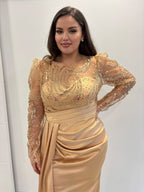 Robe de soirée dorée en satin, manches longues et buste transparents pailletés, traine sur le coté et détails plissés - vue de près 