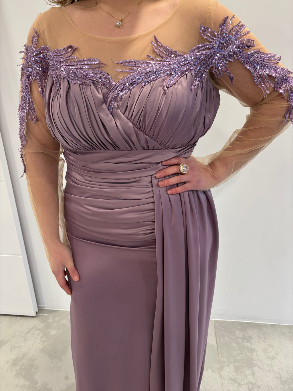 Robe de soirée mauve en satin, haut plissé avec détails pailletés, manches transparentes et traine sur le coté - vue de près  