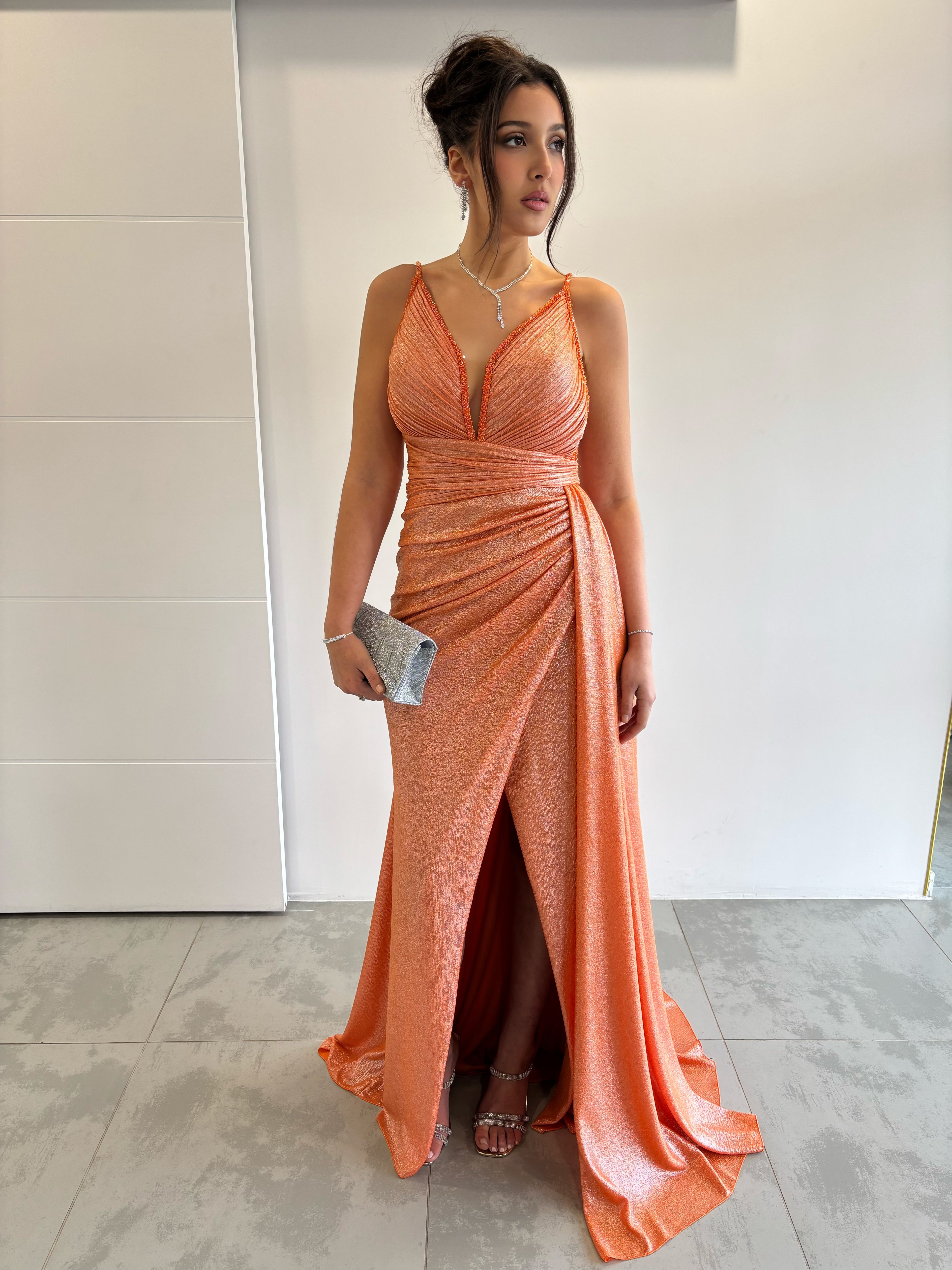 Robe de soirée longue orange pailletée avec fente, bretelles fines, col en V plongeant et traîne sur le côté