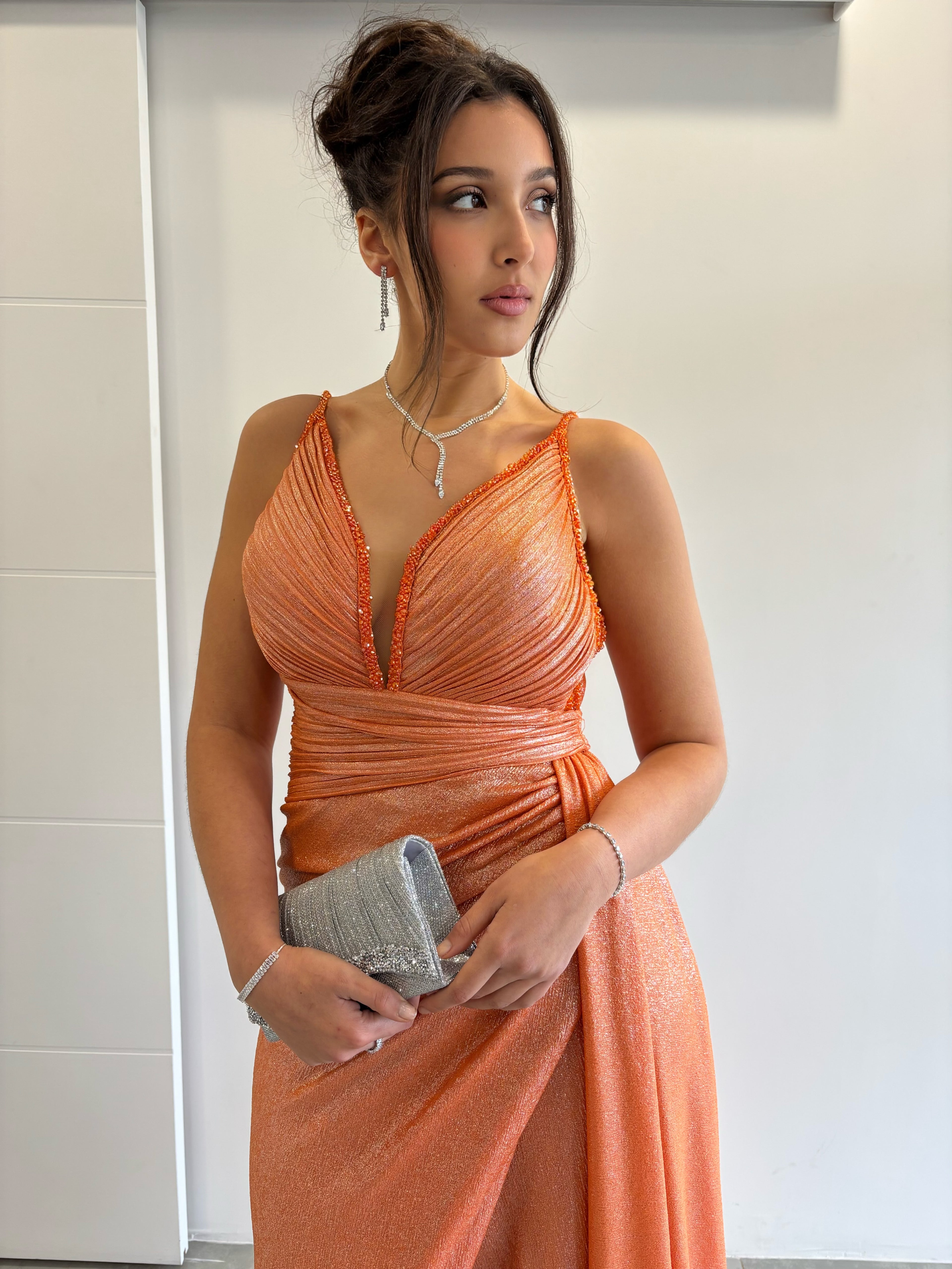 Robe de soirée longue orange pailletée avec fente, bretelles fines, col en V plongeant et traîne sur le côté