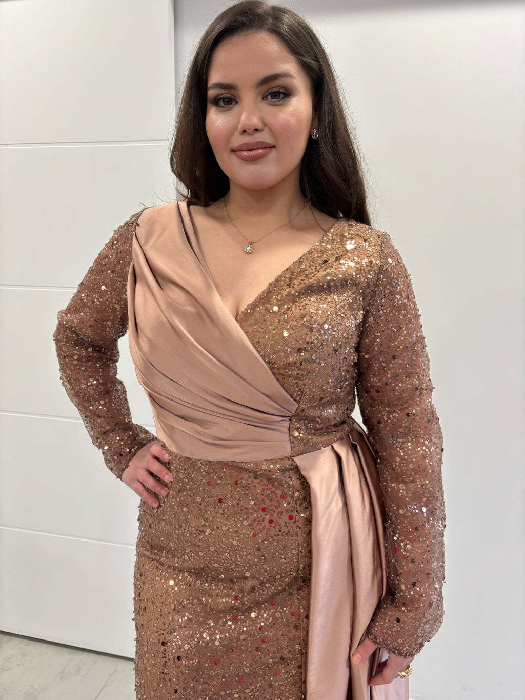 Robe de soirée en sequin en rose gold manches longues, vue sur le haut de la robe, détail plissé et traine sur le coté en satin 