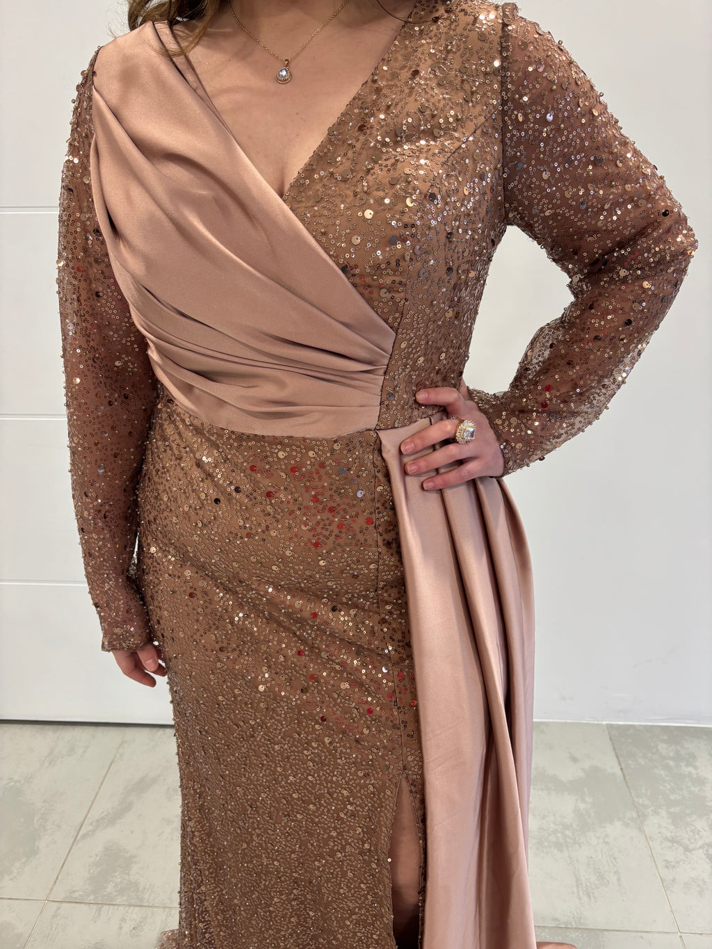 Robe en sequins rose gold à manches longues , détail plissé en satin sur la moitié du buste, traine en satin et fente sur le côté, vue de près