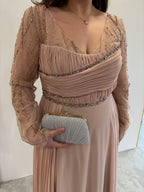 Robe de soirée rose poudrée évasée,  vue détaillée sur manches longues transparentes pailletées, buste et traine sur le coté plissés 
